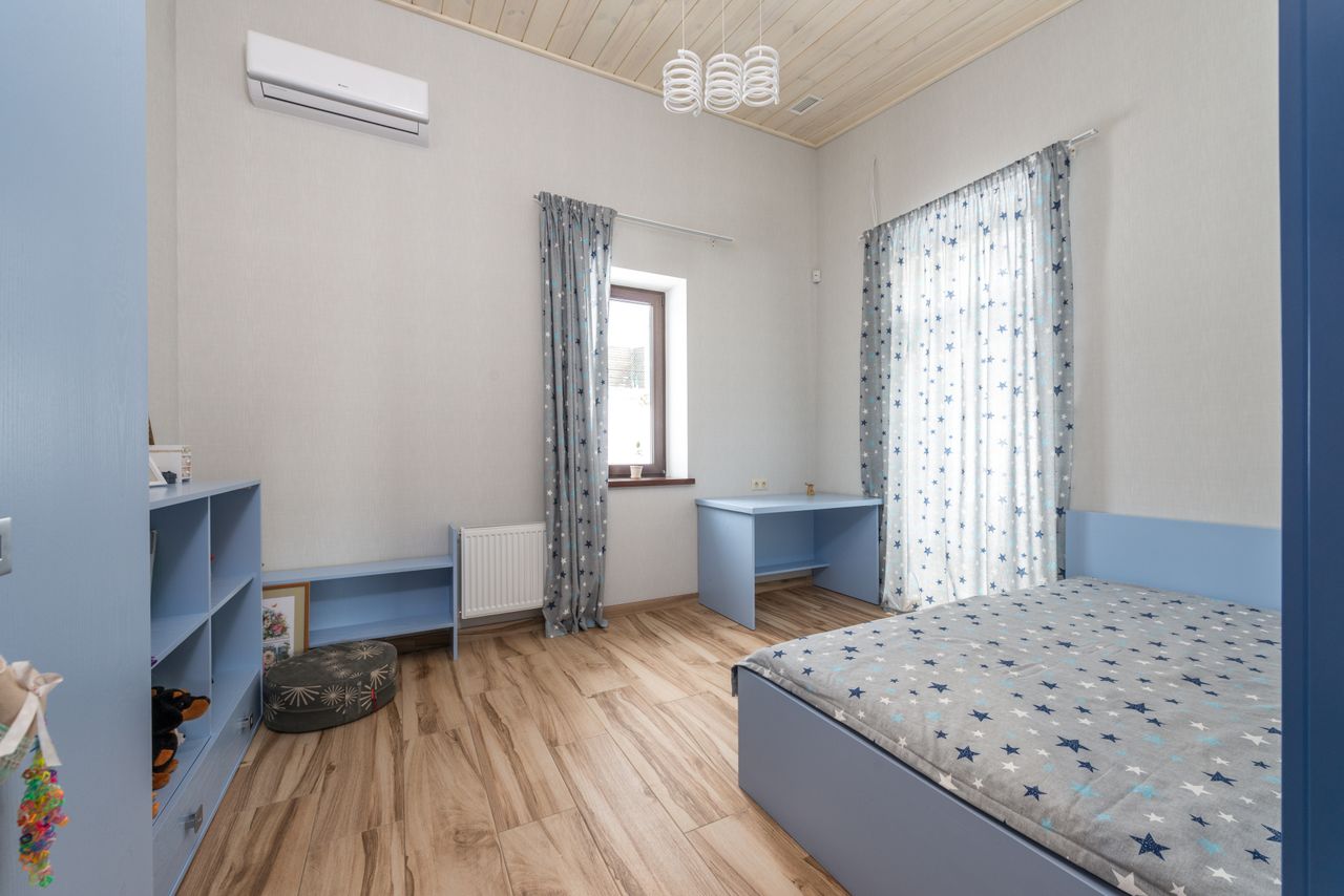 A serene and cozy bedroom with blue decor featuring wooden flooring and natural lighting.